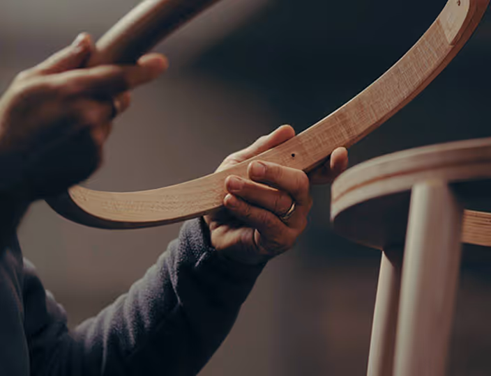 Close-up of hands assembling curved wooden furniture
